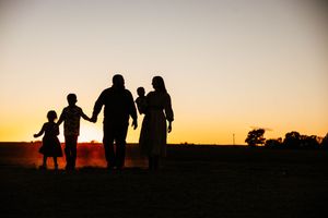Silhouettes of people walking together against a vibrant orange sunset sky.