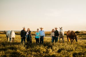 Group portrait with horses in a sun-drenched pasture during golden hour.