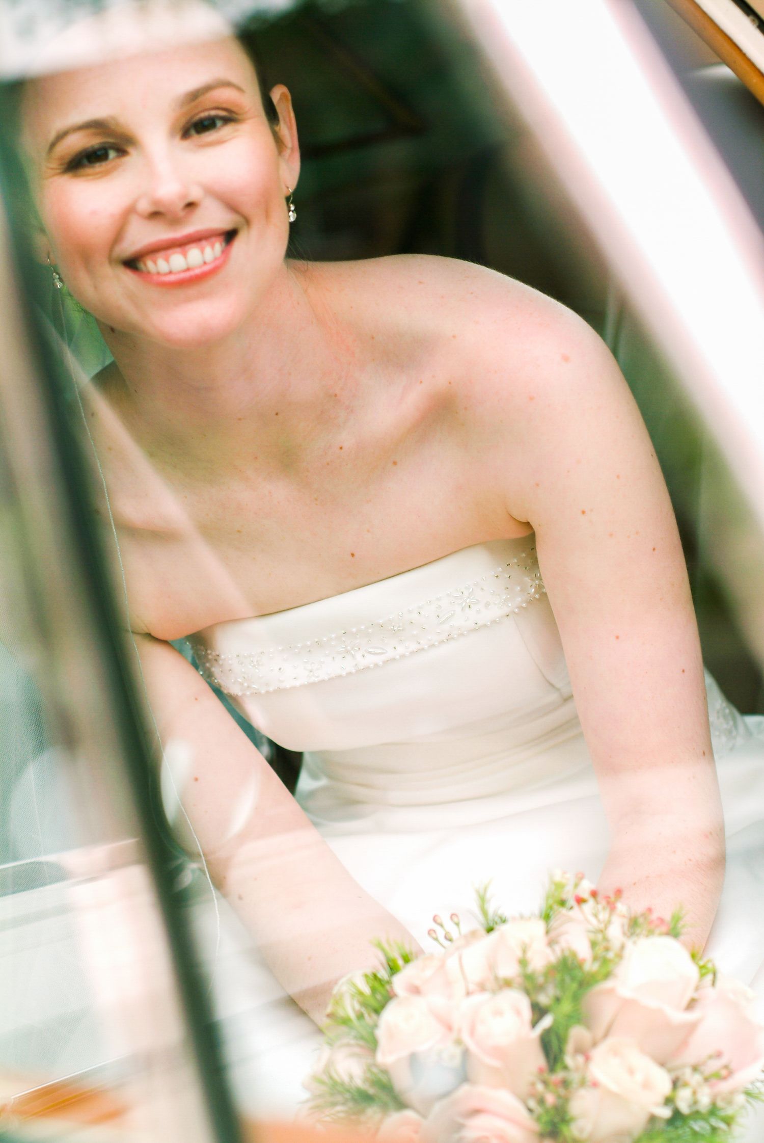 A bride in a strapless white gown holding a soft pink bouquet.