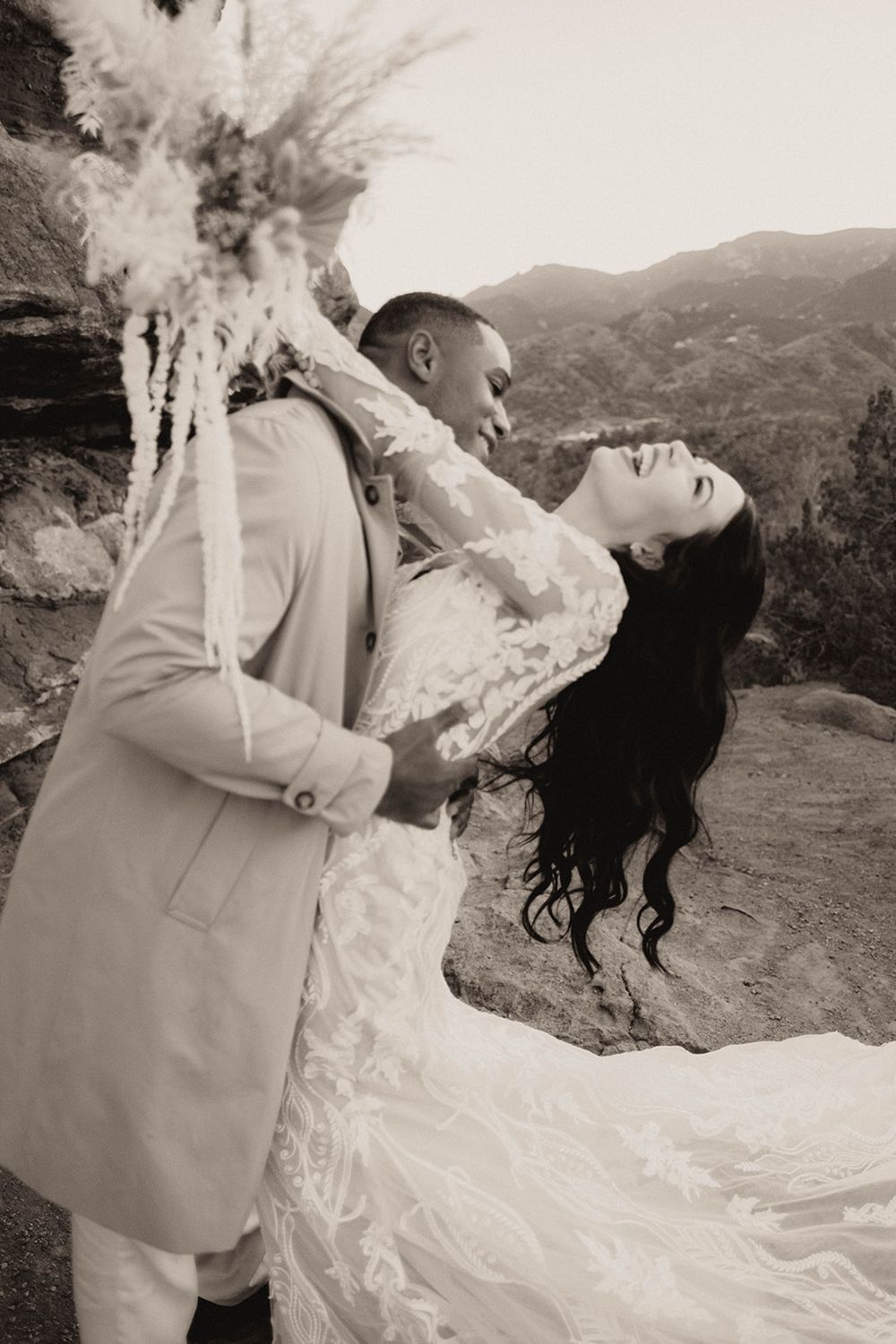 Black and white photo of groom dipping bride in lace gown at Red Rocks mountain wedding.