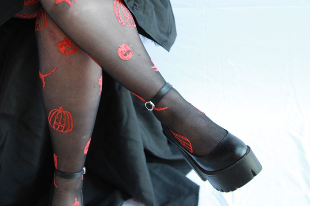Close-up of pumpkin-patterned tights with platform shoes and black skirt.