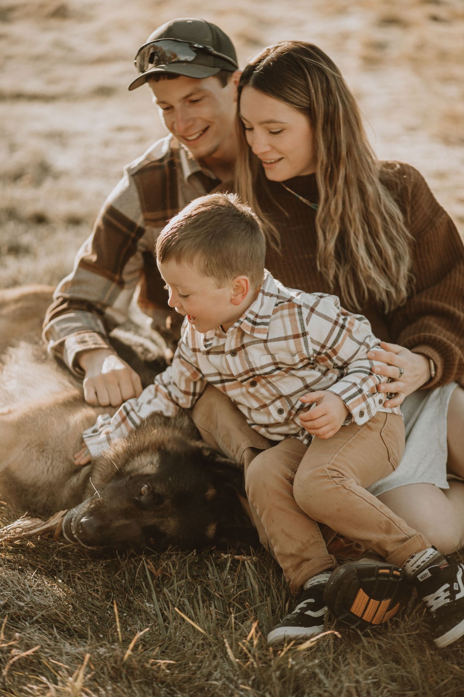 Family and their dog sharing a tender moment in golden sunlight.