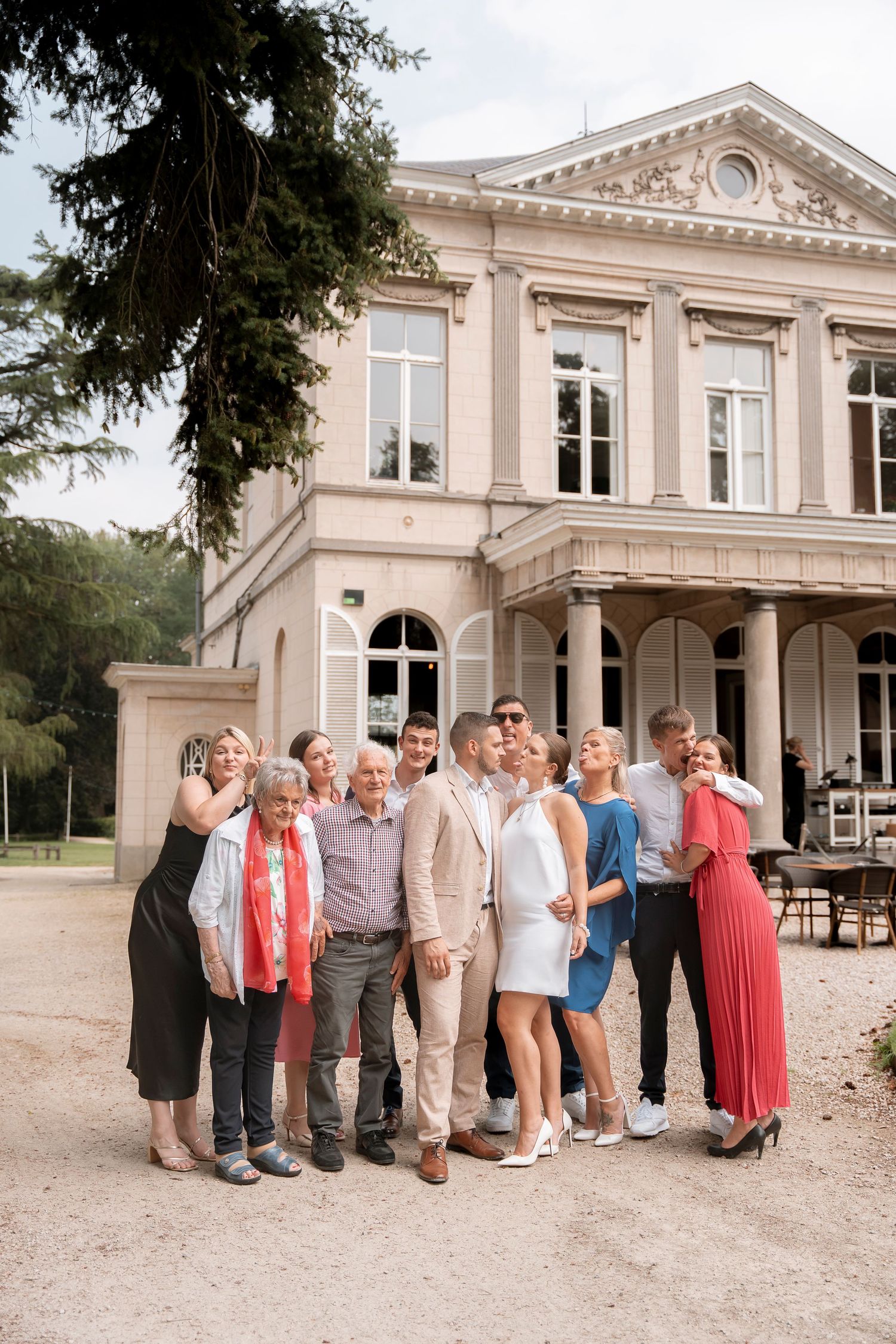 Family and friends gather for a group photo in front of a historic mansion.