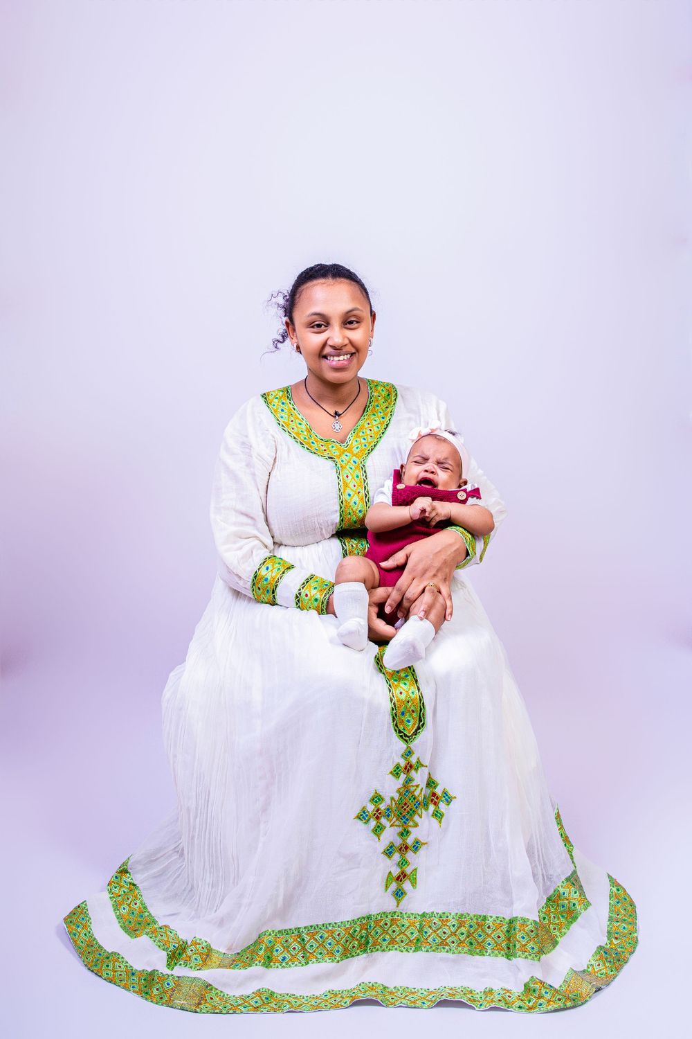 Traditional Ethiopian dress in white with vibrant green embroidery worn for a formal portrait session.