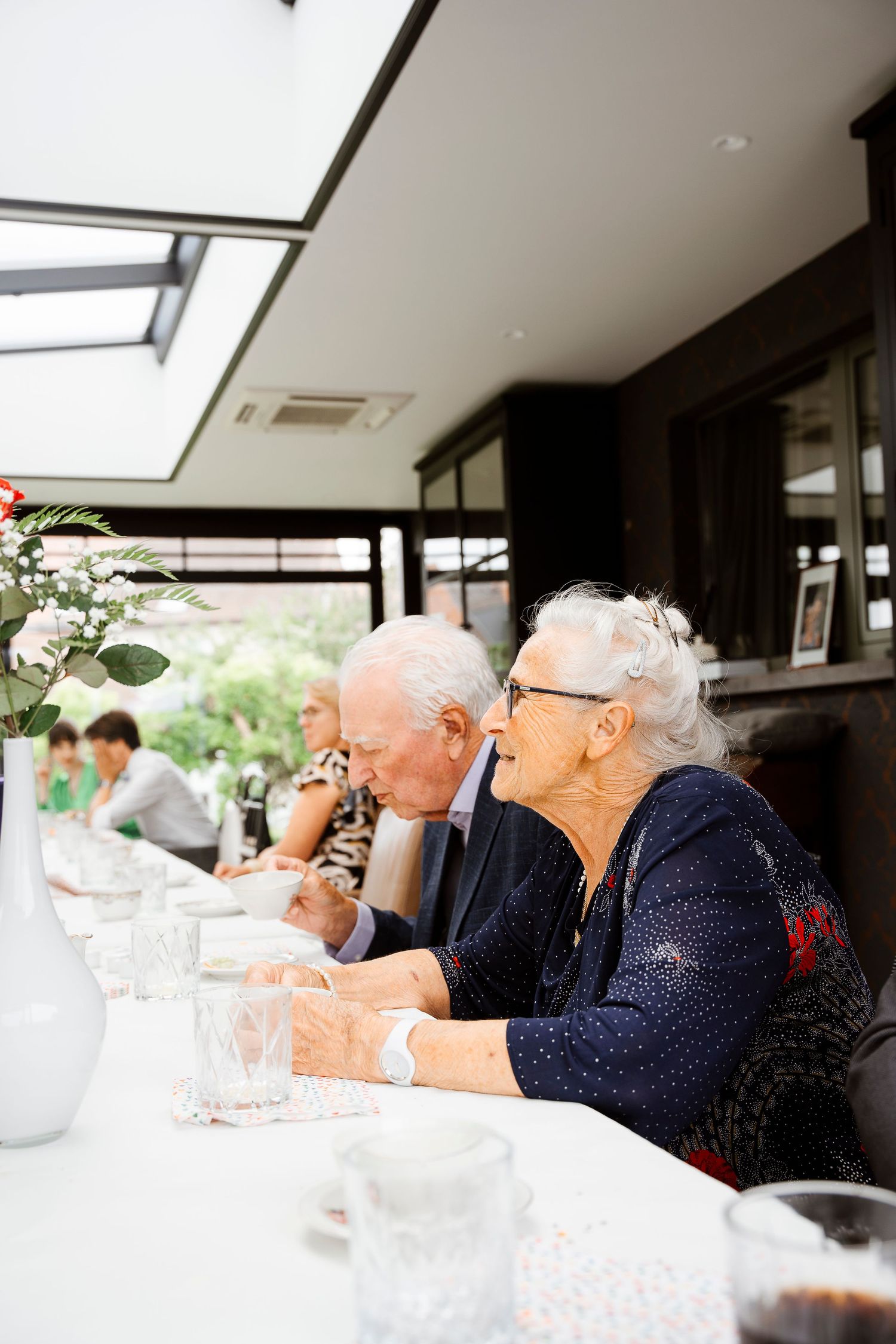 Guests enjoying a meal at an elegant dining table with natural light streaming through windows.