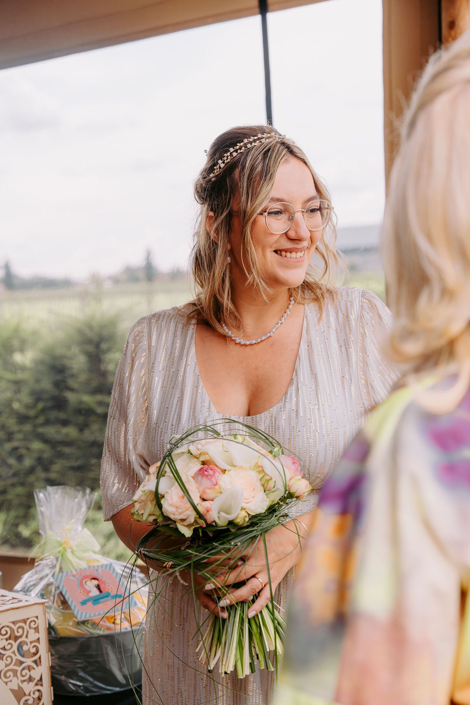 Person holding beautiful bouquet of pink and white roses with decorative wreath.