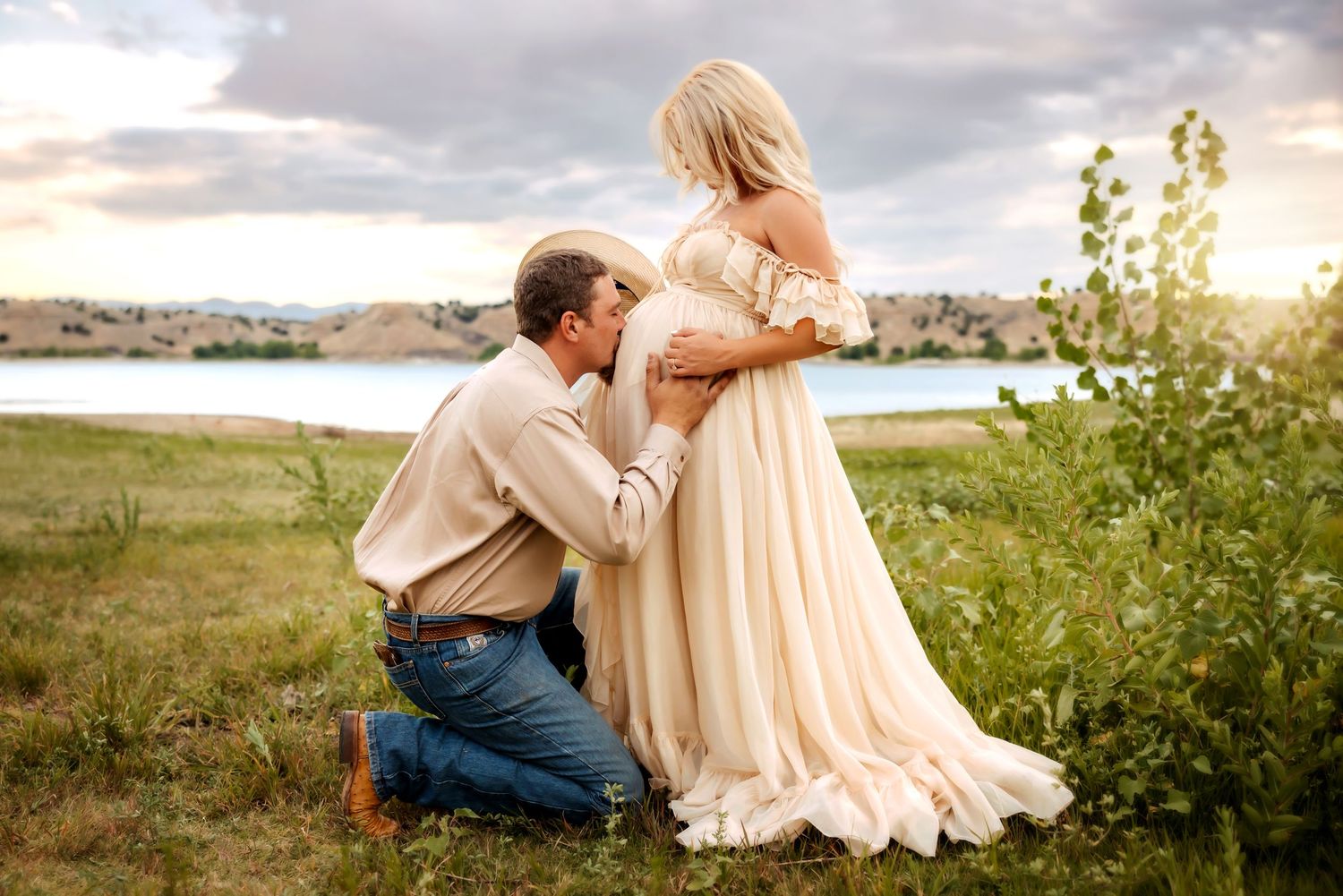 A maternity photo taken by a serene lake at golden hour. Pueblo Photographer