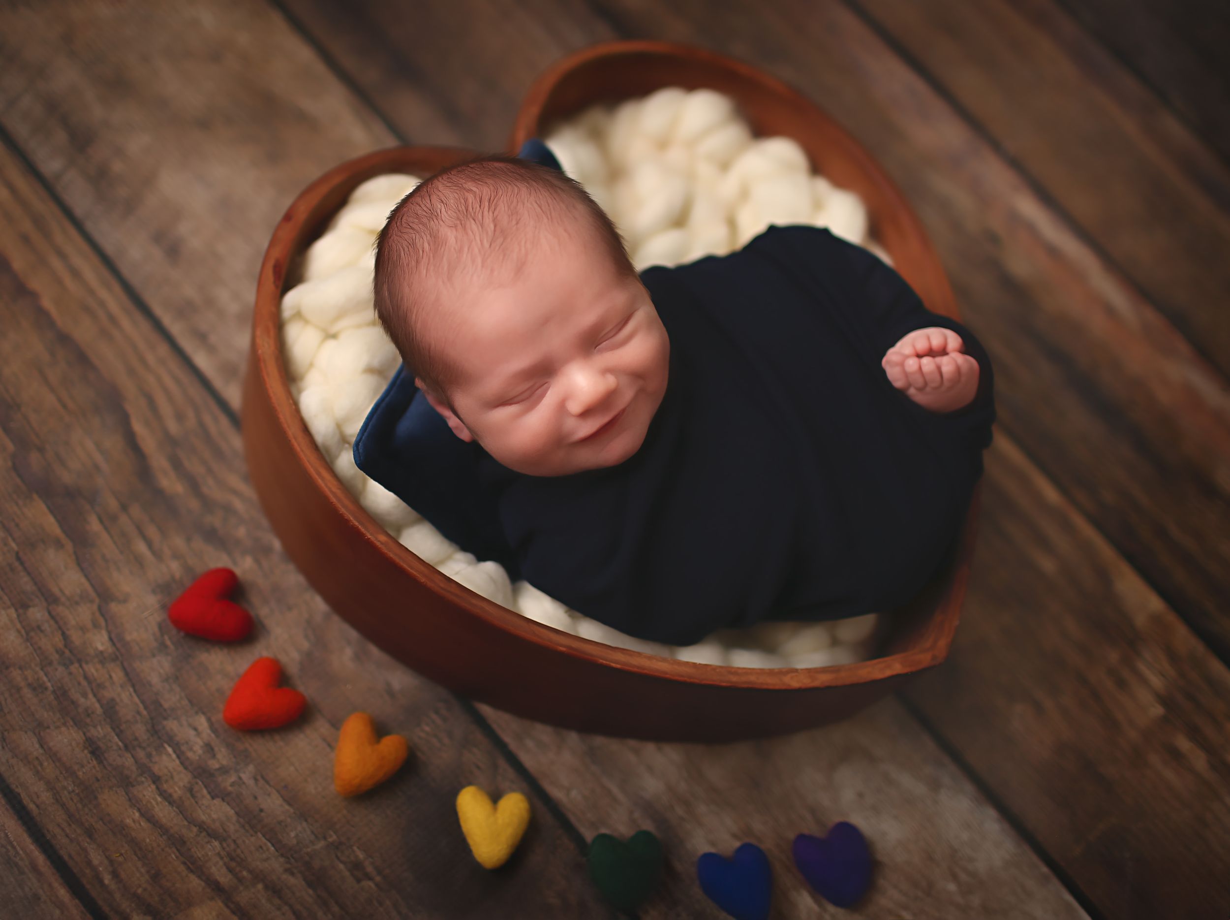 Newborn baby boy wrapped and placed in heart shaped bowl