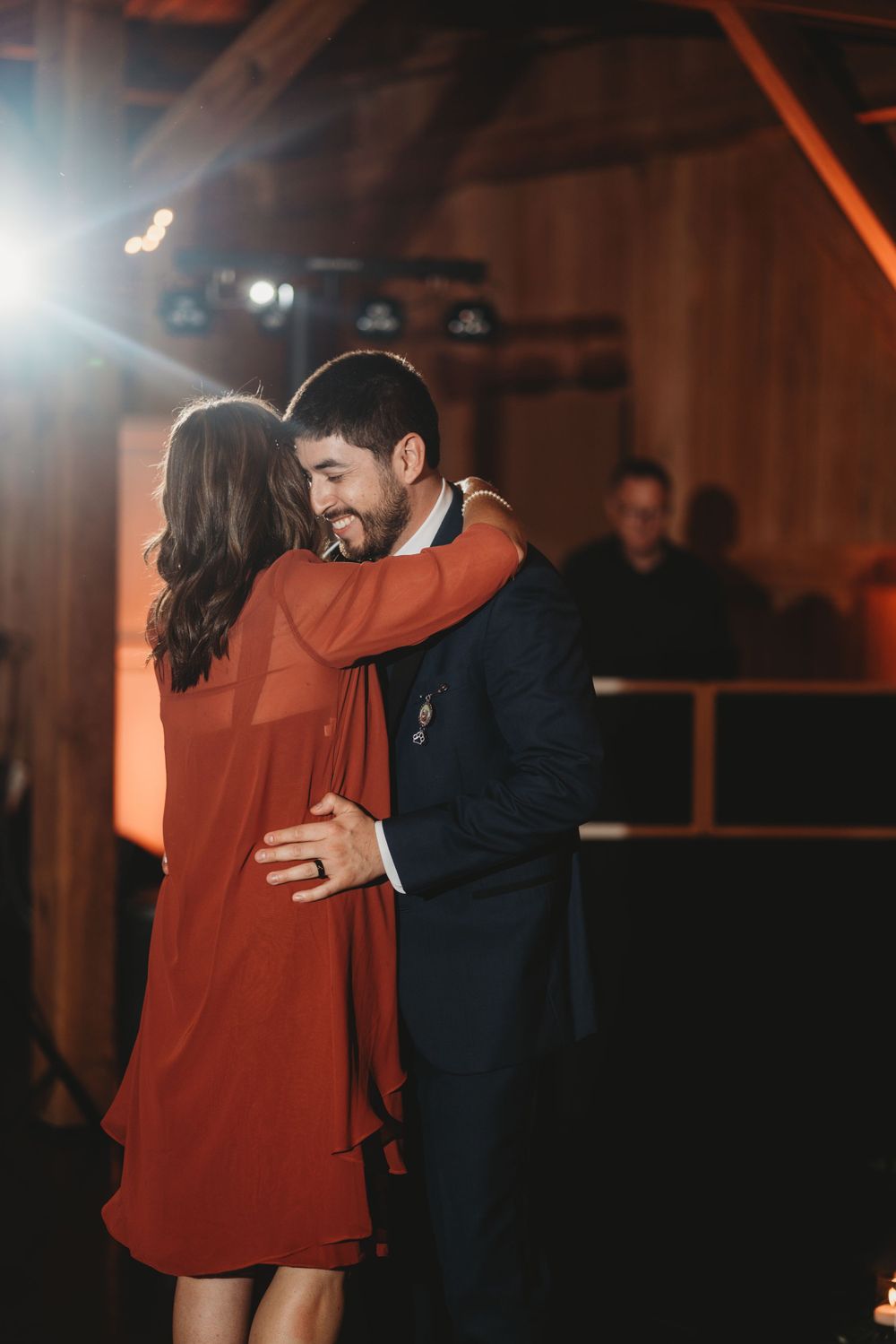 A couple shares an intimate dance in a dimly lit rustic venue with a woman in red dress.