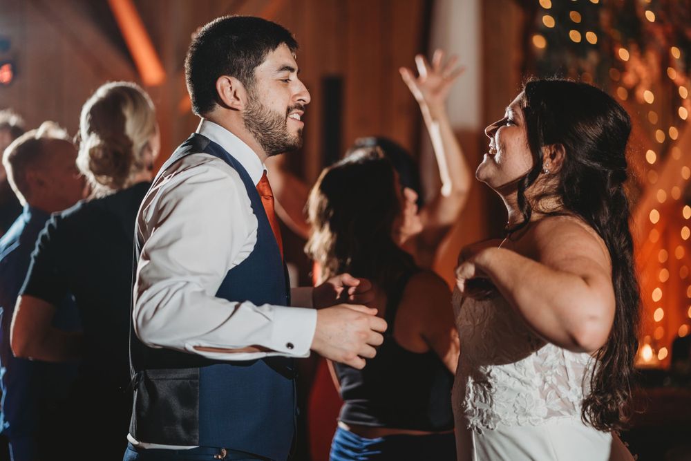 Wedding reception dance party in a rustic barn venue with string lights.