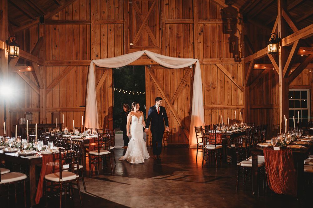 Elegant barn wedding reception setup with draped fabric and romantically lit dining tables.