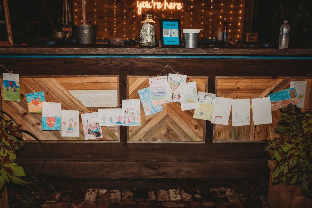 Rustic wooden bar display with children's drawings and artwork pinned across it.