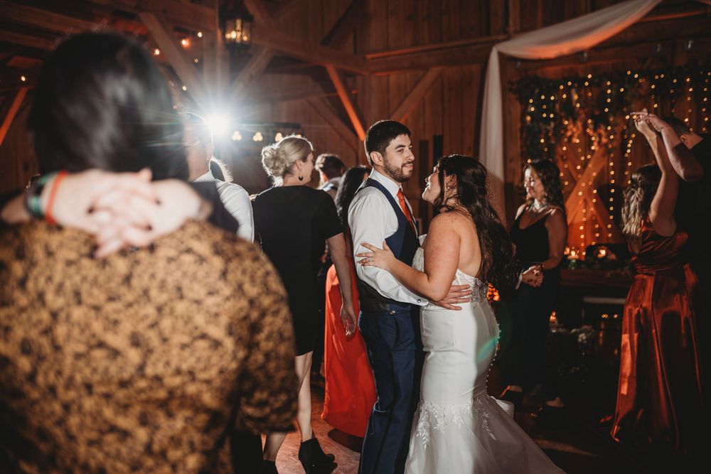 Couples dancing during an intimate barn wedding reception with string lights and decorations.