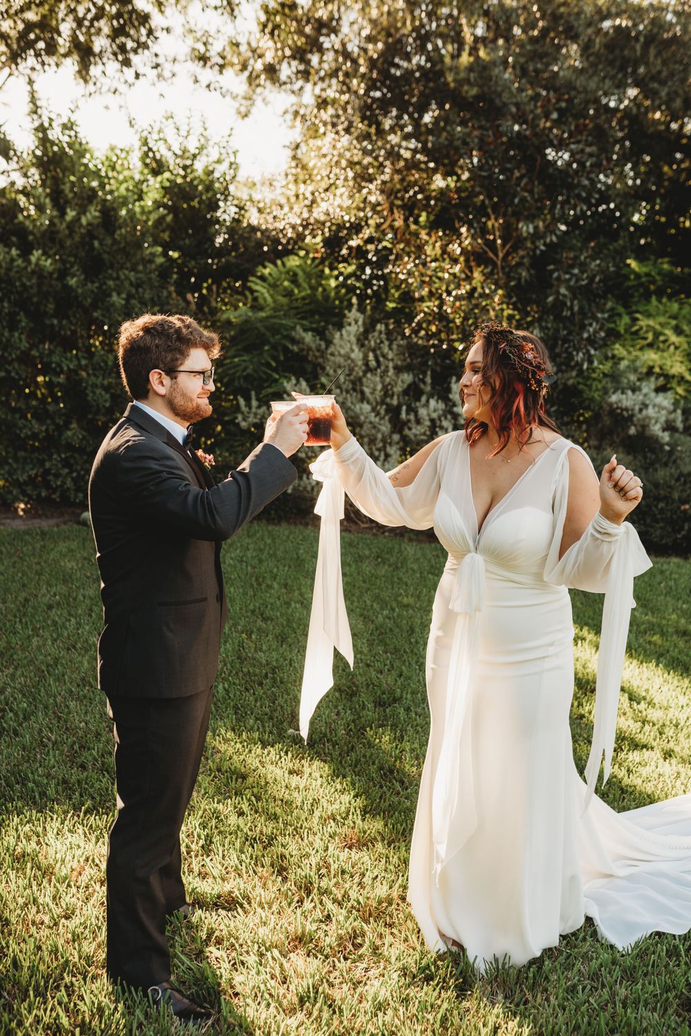 Couple dancing playfully with ribbons during outdoor garden wedding photoshoot.