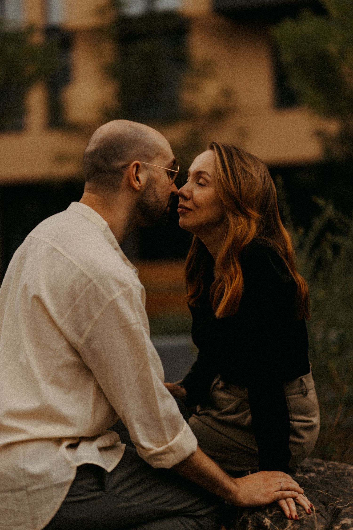 A romantic moment between two people sitting outdoors near apartment buildings.