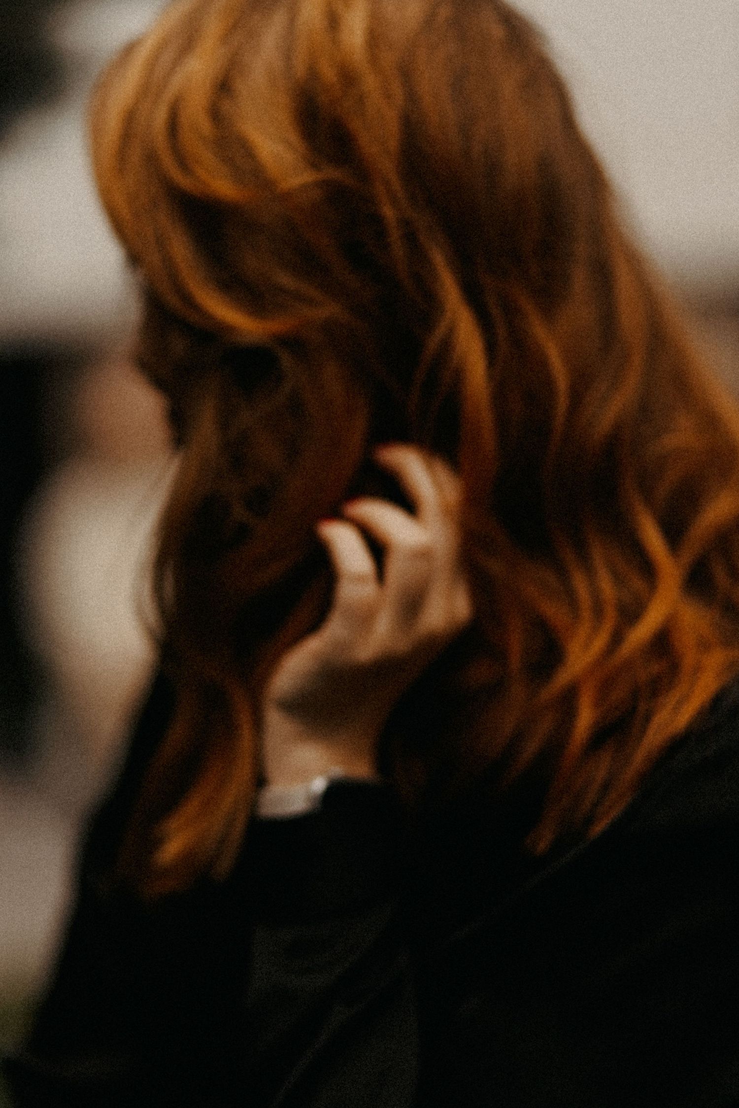 Close-up of flowing red hair against dark background.