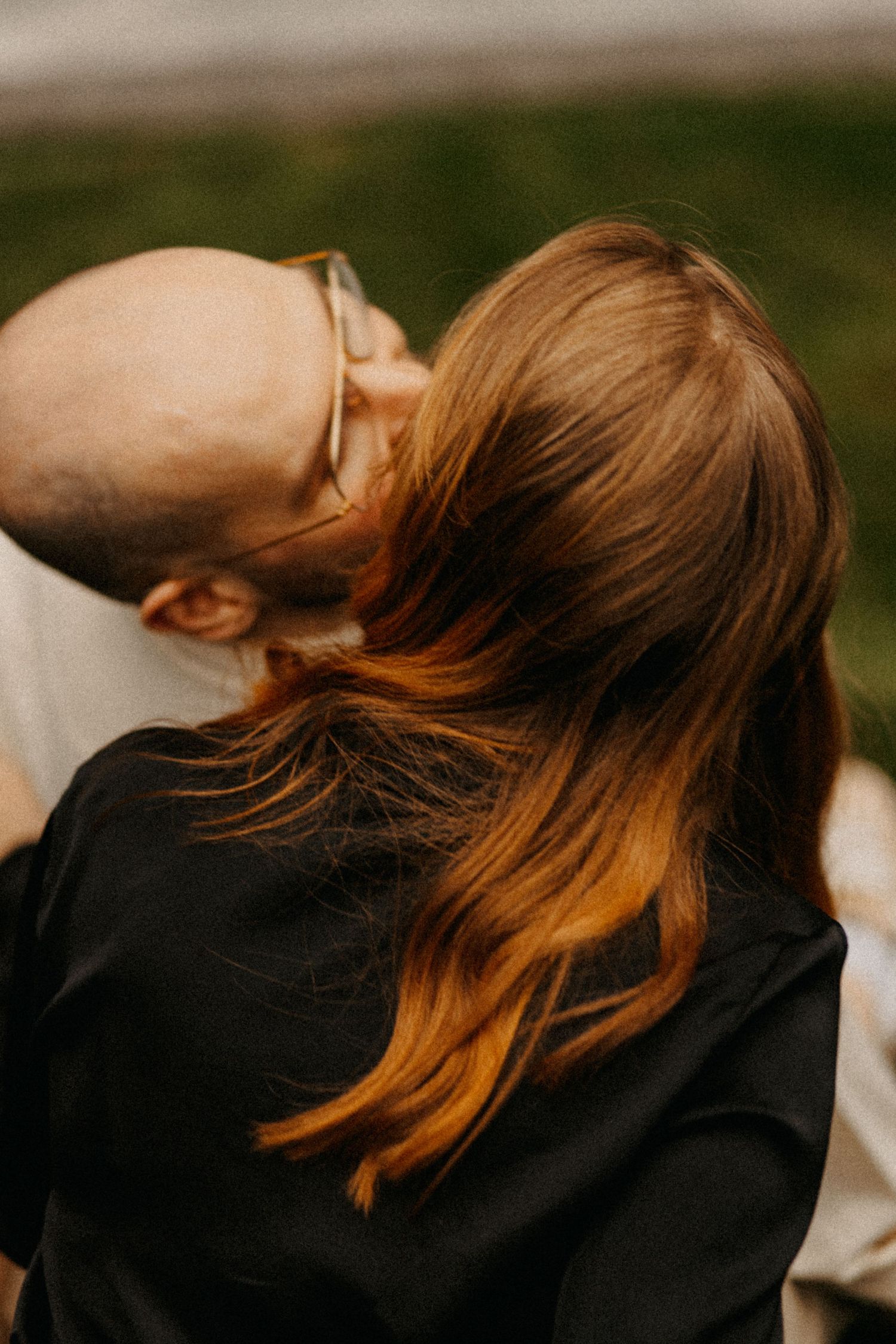 A tender moment captured between two people embracing outdoors with soft lighting and warm tones.