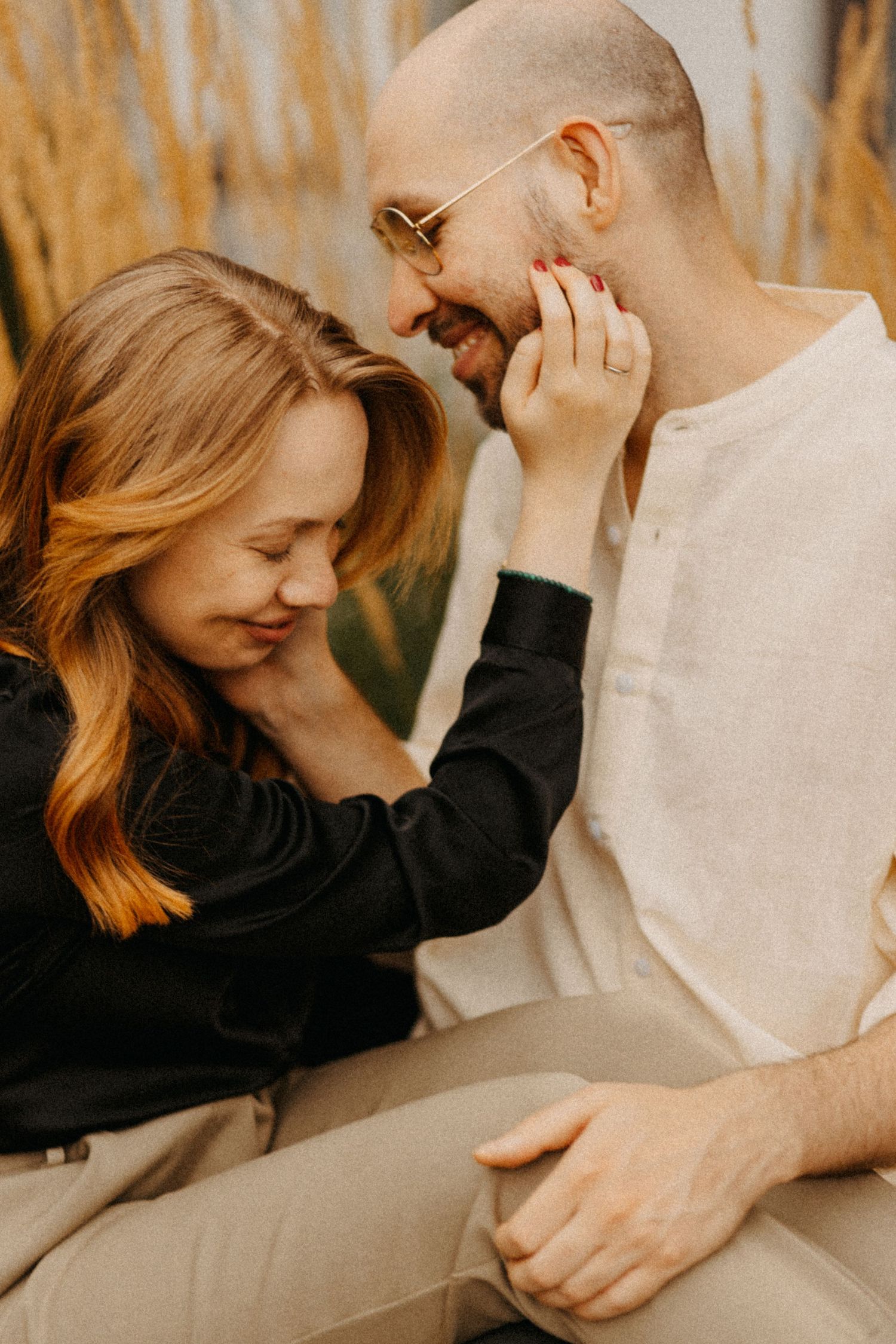 A candid romantic moment between a couple laughing together outdoors.