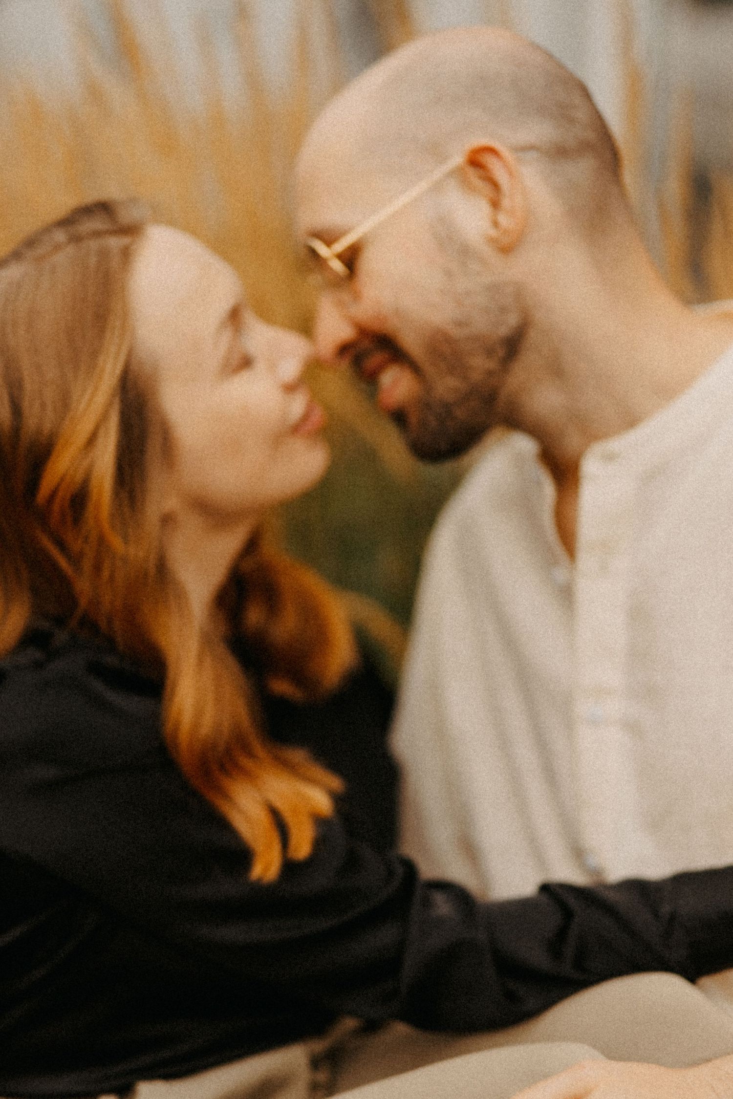 A close-up portrait of a couple sharing a romantic moment with warm lighting.