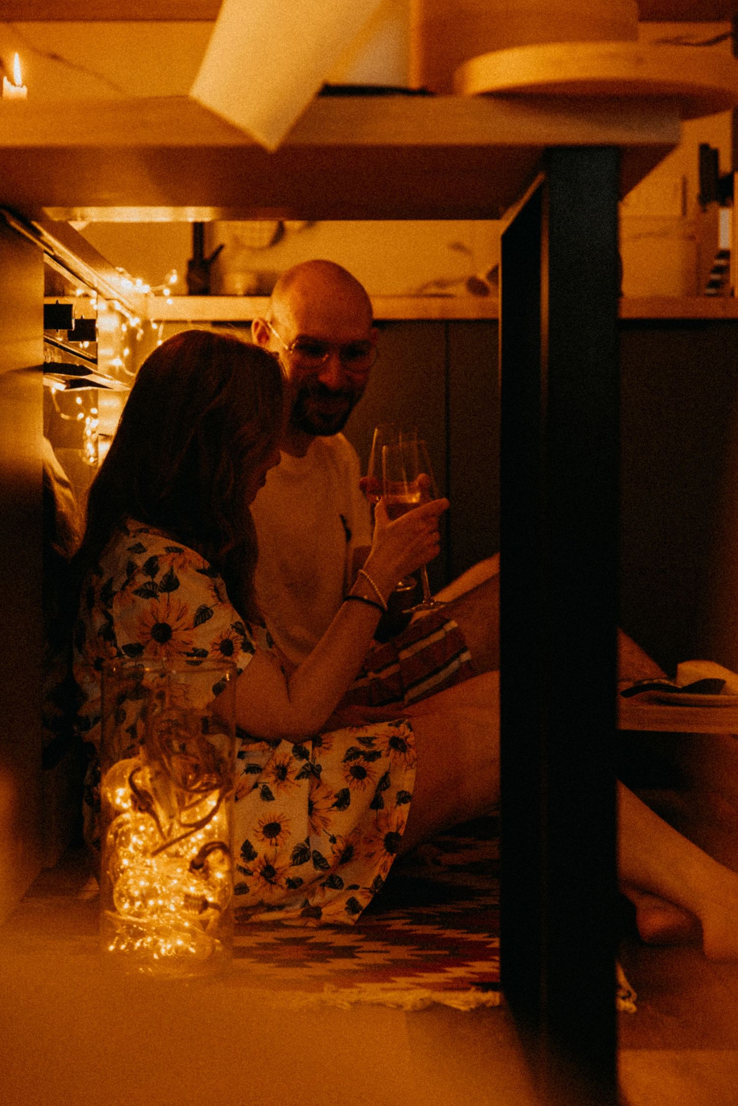 A couple sharing wine in an intimate setting with warm ambient lighting.