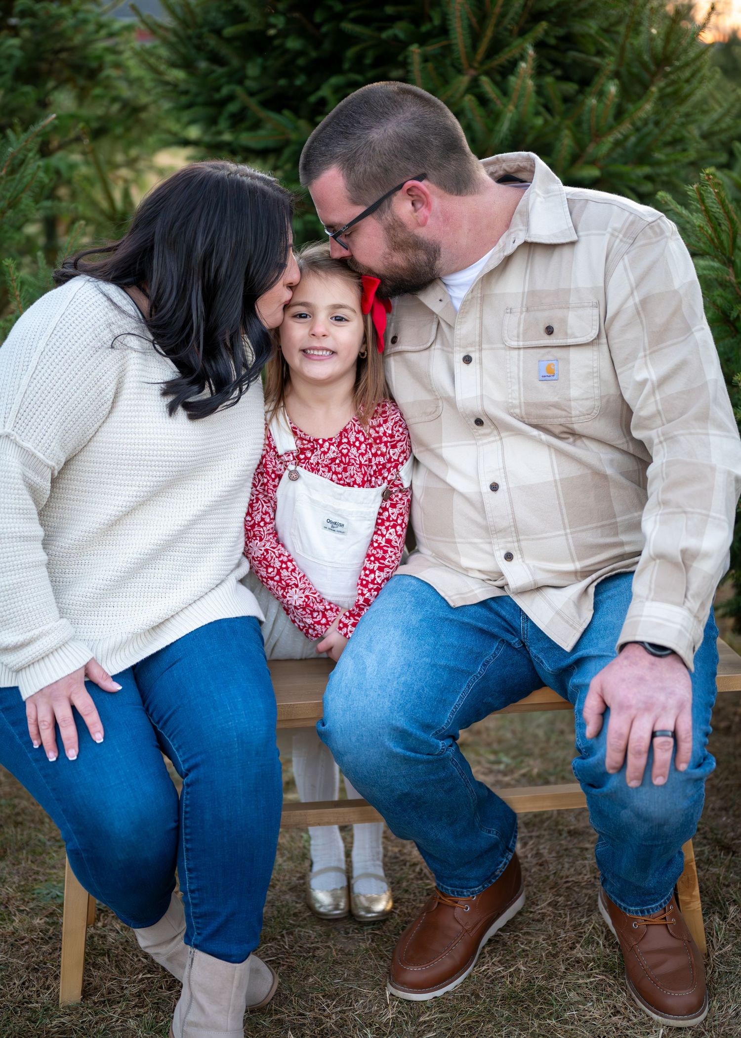 Mother and father kissing their daughters head while sitting on each side of her. Wrightstown NJ Family Photographer