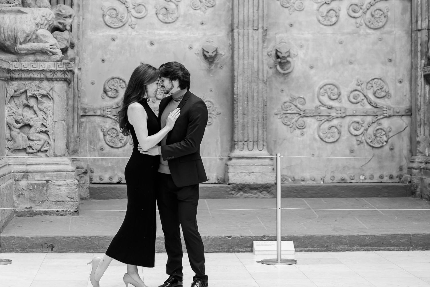 A couple dances together in an elegant historic building with ornate walls and architectural details.