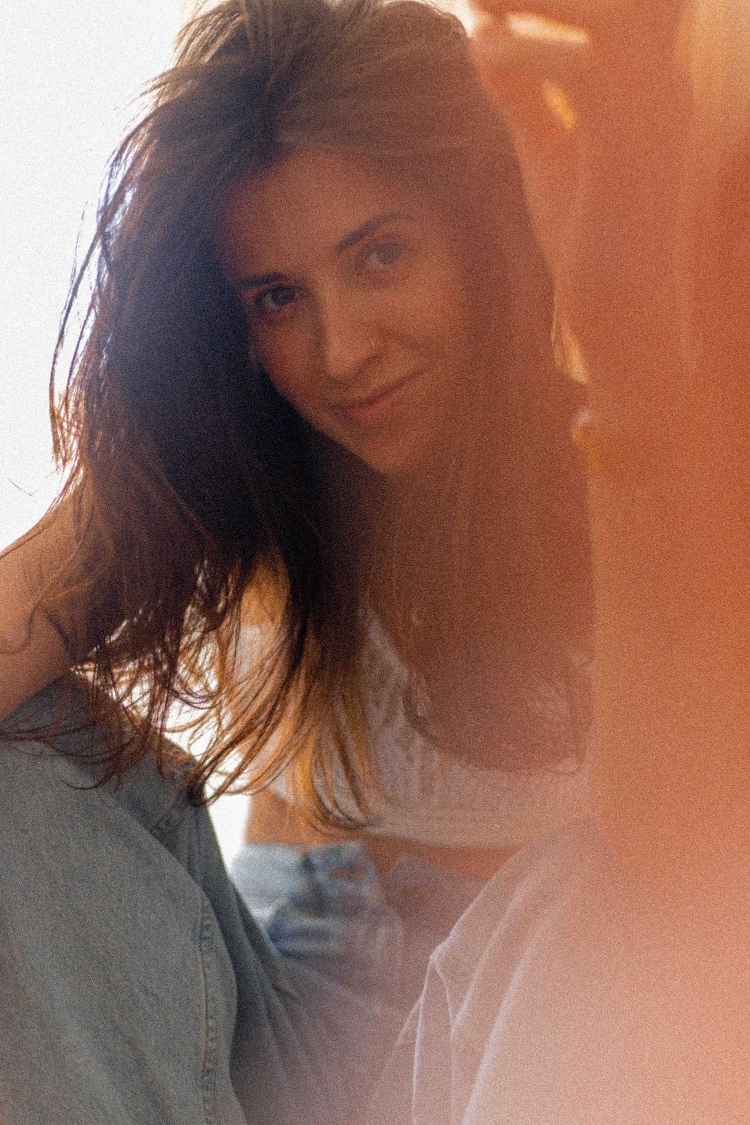 Portrait of a woman with flowing dark hair in warm sunlit ambiance.