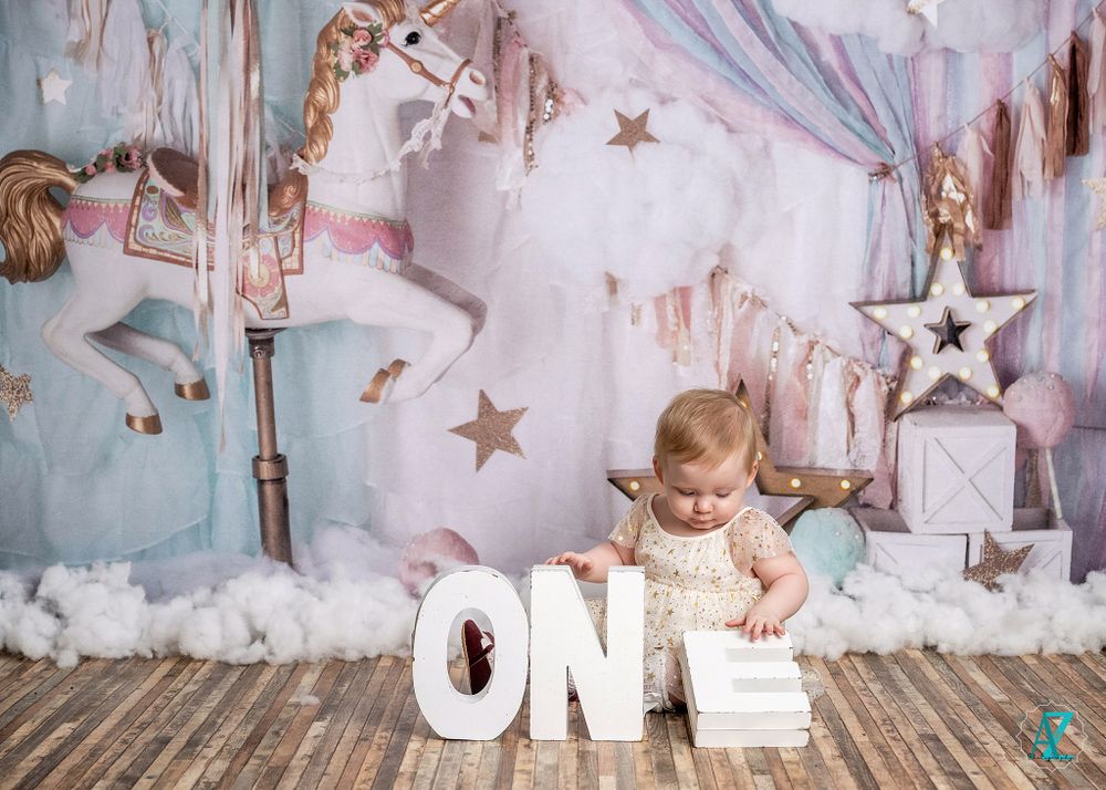 First birthday scene with wooden letters spelling ONE against dreamy carousel-themed backdrop.