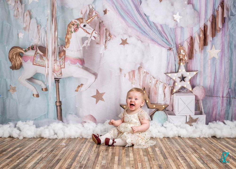 Whimsical first birthday scene with carousel horse backdrop and cloud-like decorations.