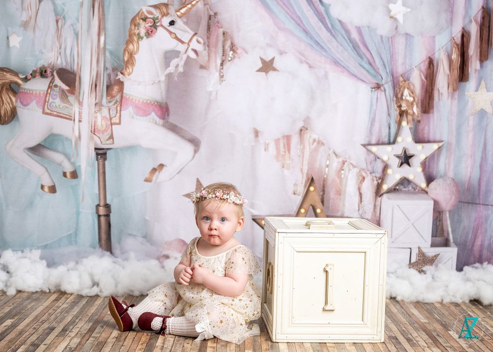 Dreamy birthday photo setup with number one cube and carousel horse in soft pastel colors.