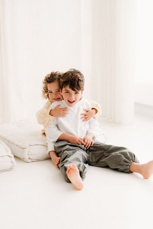Broer en zus lachen samen tijdens een familieshoot in studio.