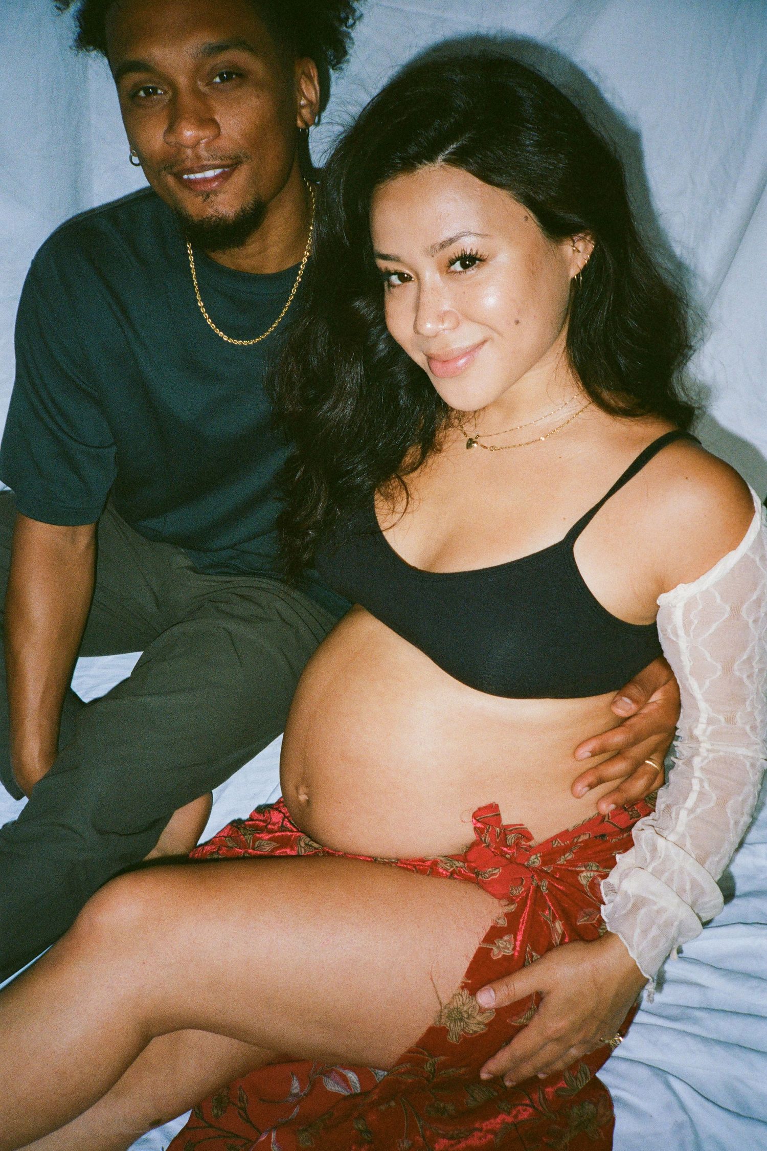 Intimate maternity photos showing a couple embracing against white backdrop.