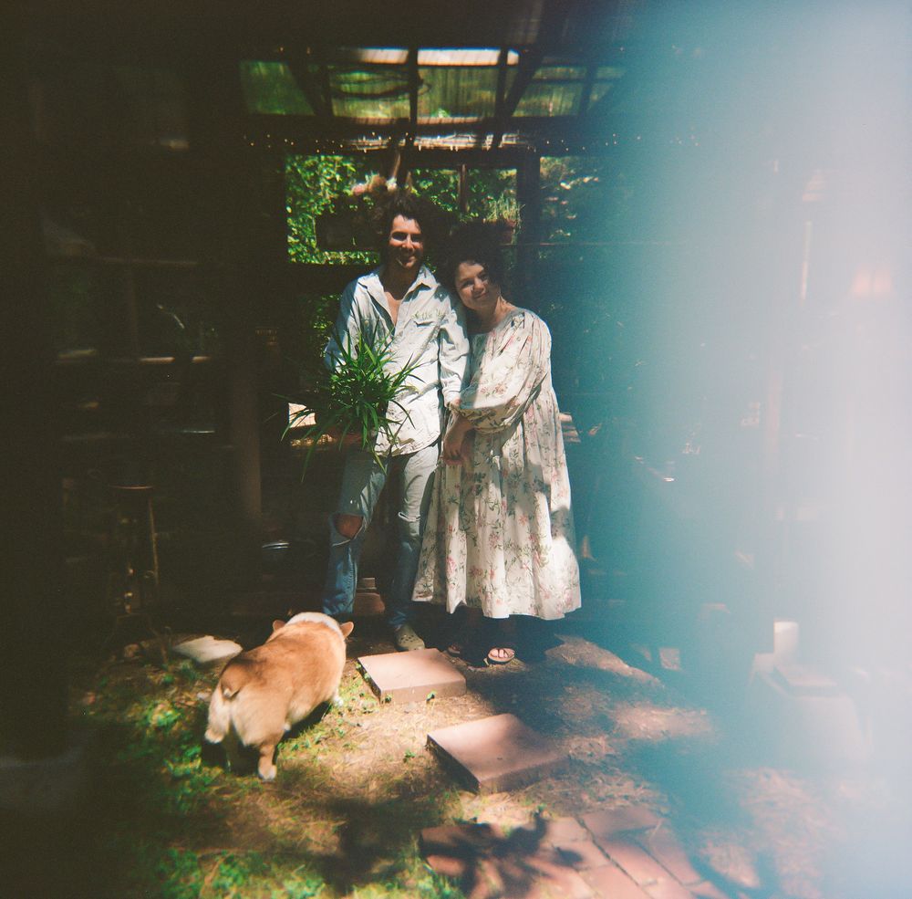 Dreamy film photo of people and corgi in garden greenhouse setting.