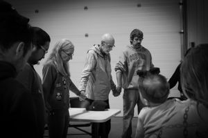 Group of people gathered around table in meeting or workshop setting.