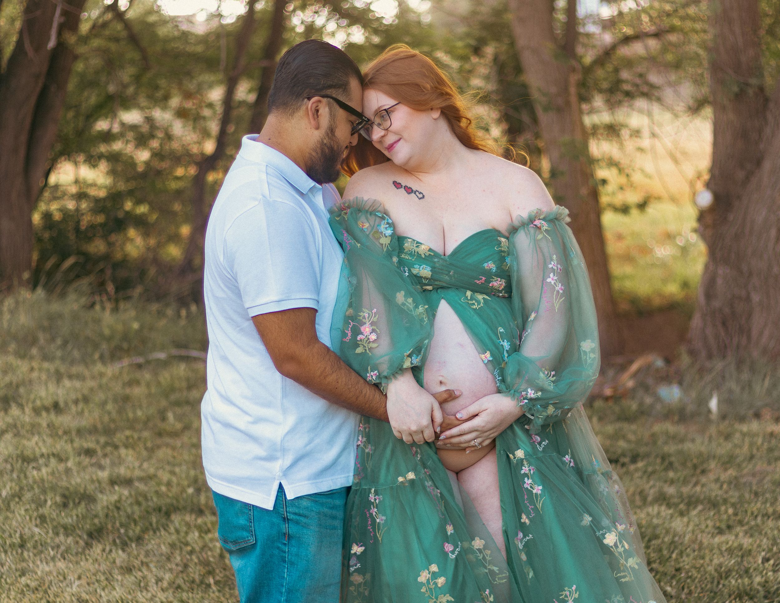 A couple shares an intimate moment outdoors wearing turquoise and white outfits.