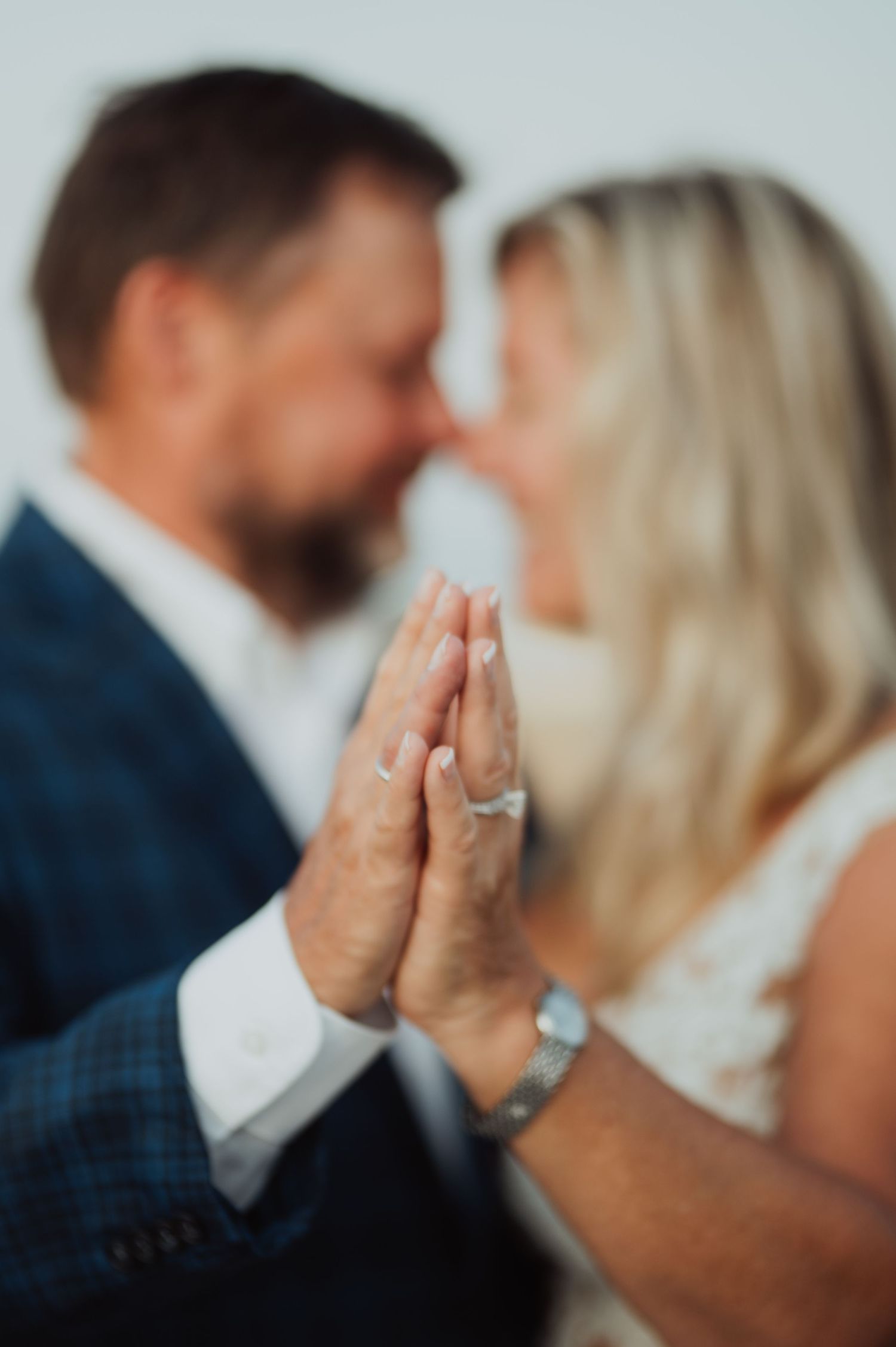 Close-up of clasped hands showing engagement ring during intimate moment.