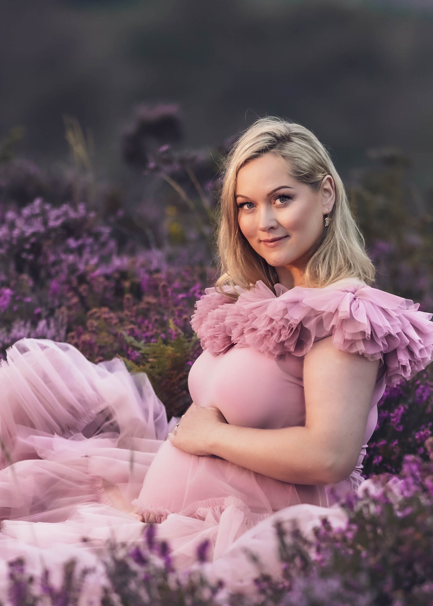 Romantic portrait in pink tulle dress surrounded by purple heather flowers.