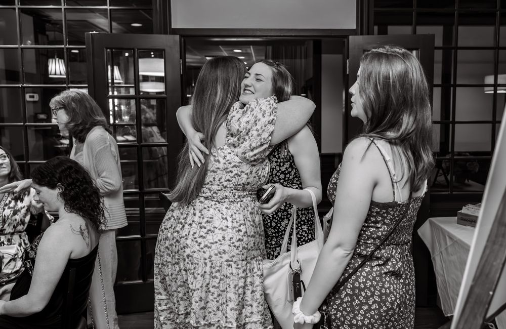 Black and white photo of party guests socializing at indoor venue.