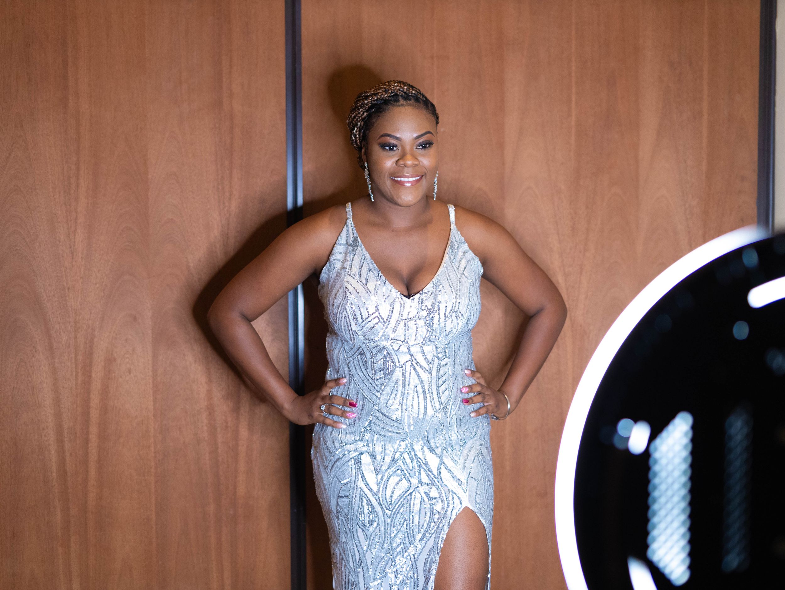 A woman poses in an elegant white sequined gown with a high slit.