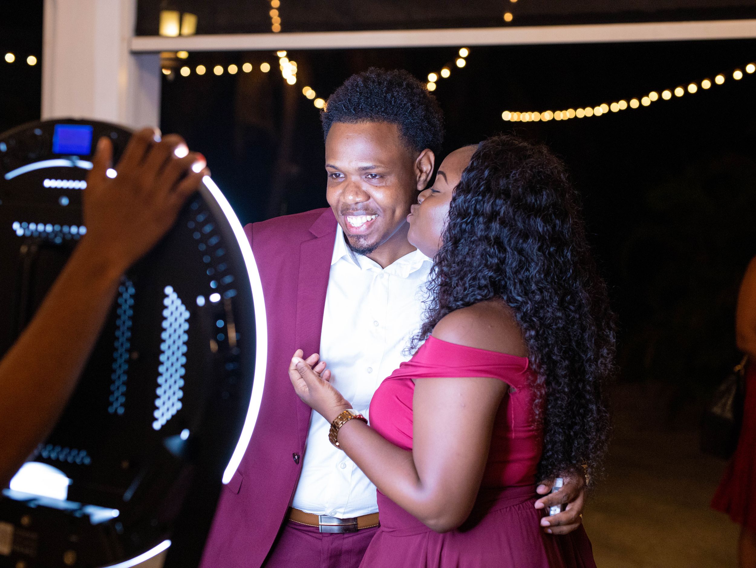 A couple sharing a joyful moment together while dressed elegantly in burgundy and white at an evening event.
