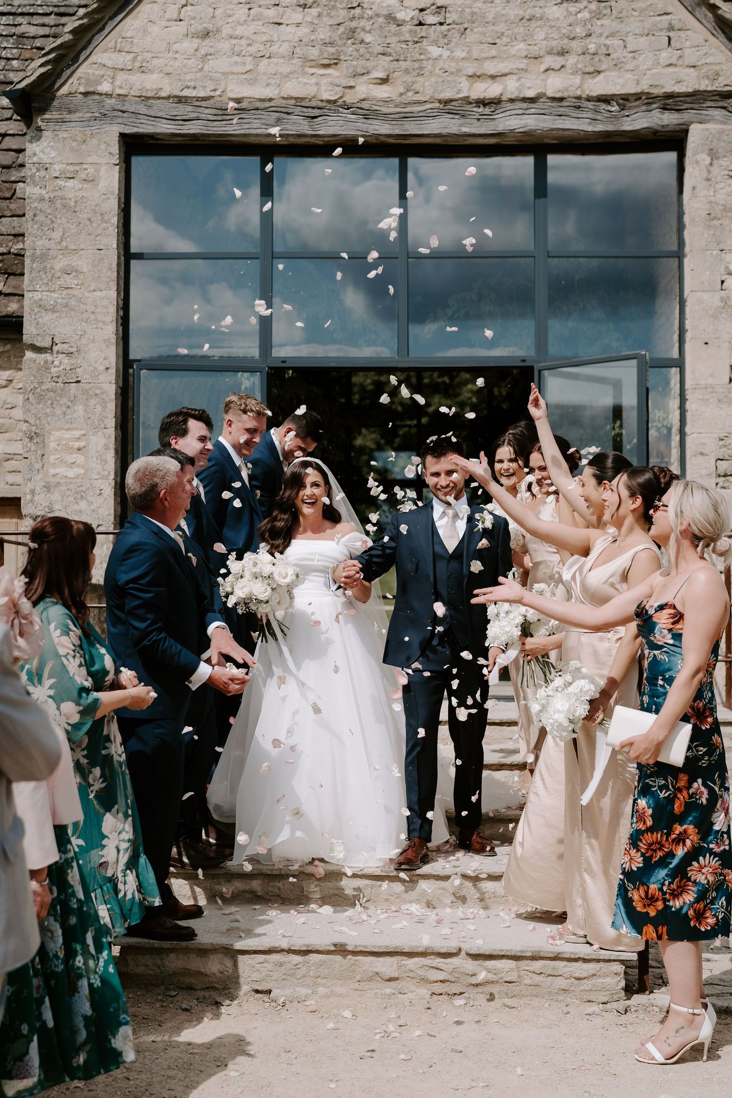 bride and groom walking though confetti throw at yardspace old gore in cirencester