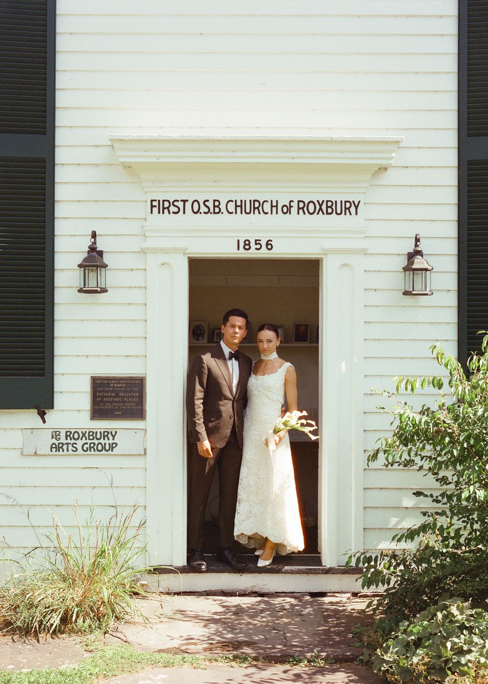 Bride and groom posing in doorway of First O.S.B. Church of Roxbury, established 1856, on their wedding day.