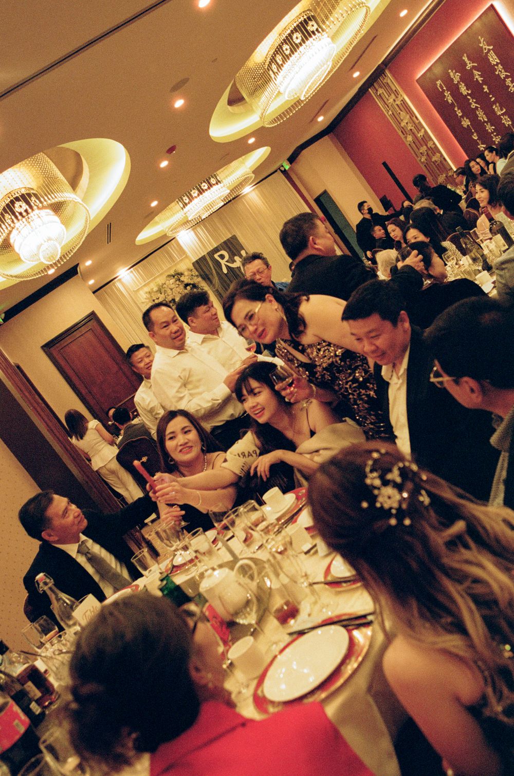 Guests gathered around a banquet table at an elegant Asian wedding reception dinner in a warmly lit restaurant.