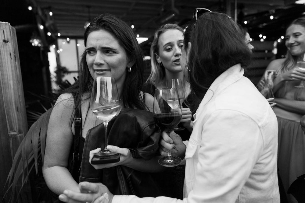 Friends enjoying drinks and conversation at a casual gathering in a dimly lit venue.