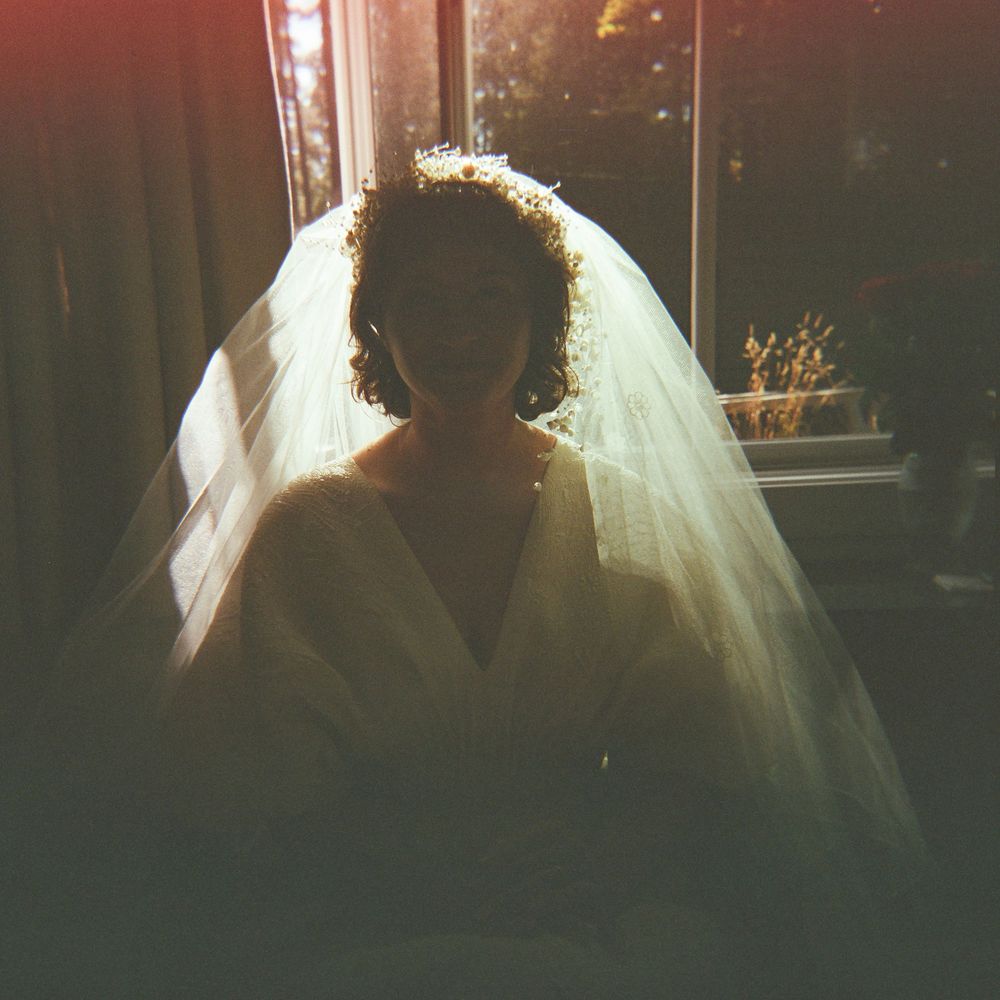A backlit silhouette wearing a wedding veil creates a dramatic lighting effect.