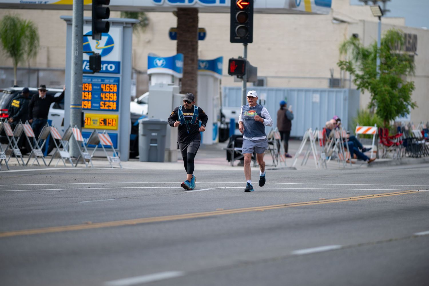 People walking and crossing at an urban intersection with traffic signals and signs.