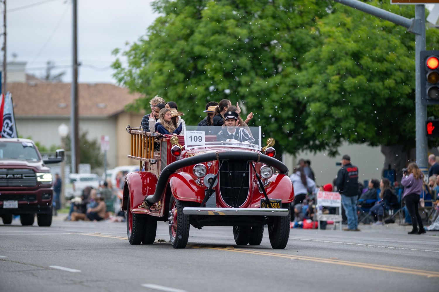 A parade of tractors and agricultural equipment driving down a city street during a community celebration.
