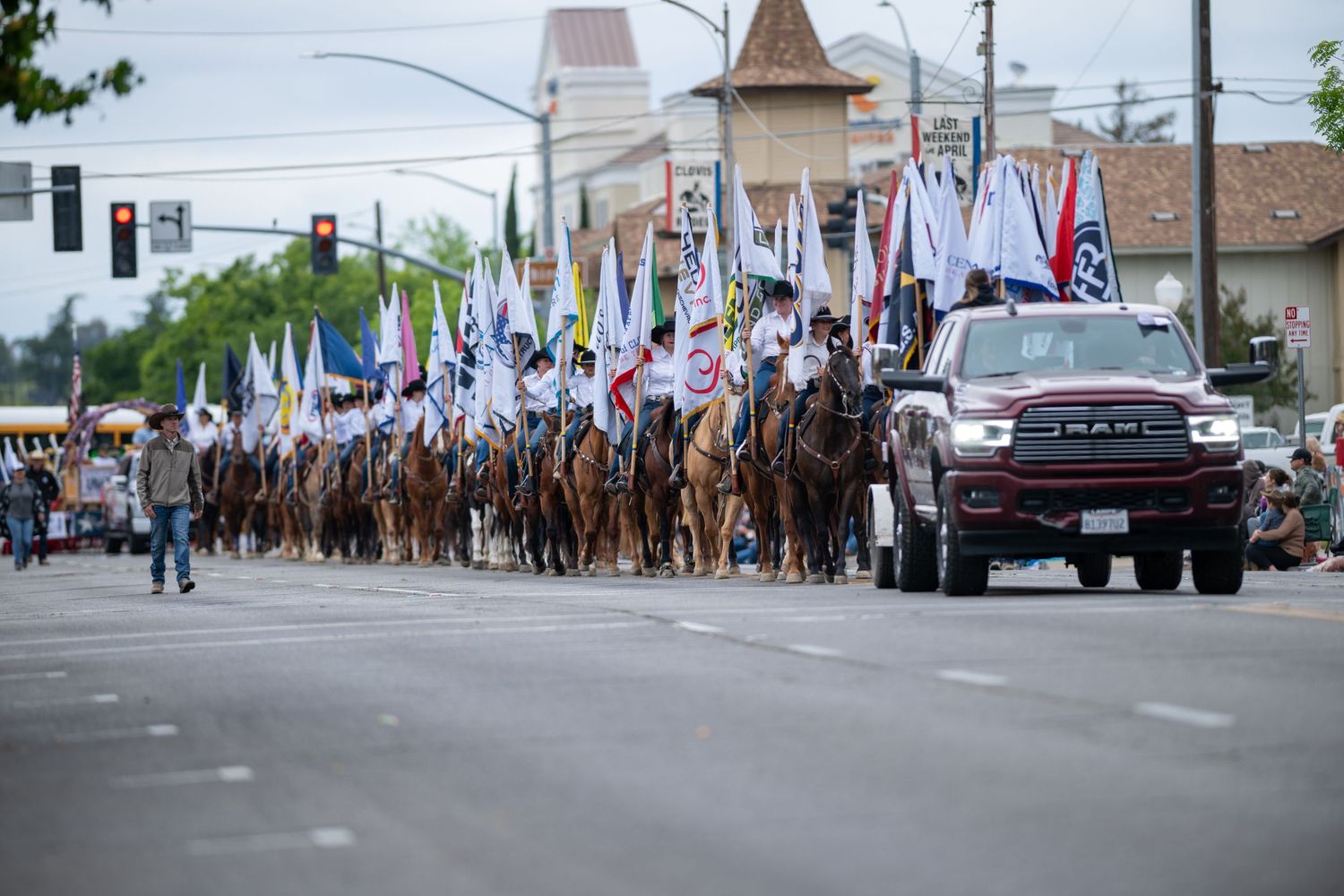 Large parade procession with multiple horseback riders moving down a city street.