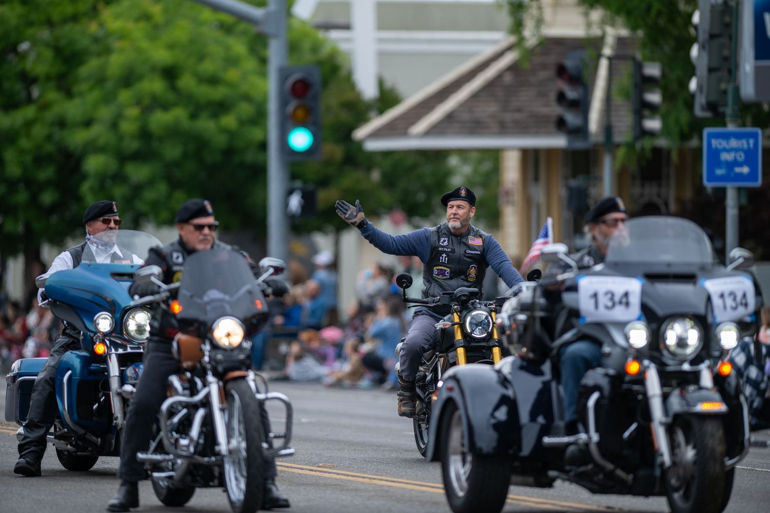 Motorcycles and riders participating in a community parade along a downtown street.