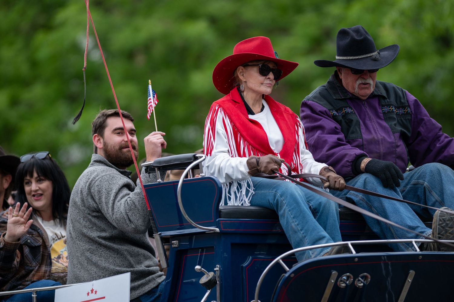 Parade participants ride in a classic horse-drawn carriage.
